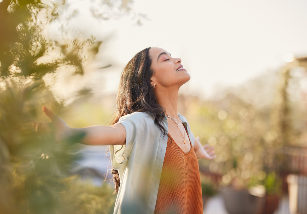 woman basking in the sun with her arms spread in gratitude